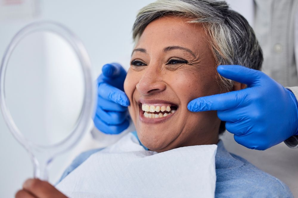 Dental patient smiling while a dentist checks her teeth