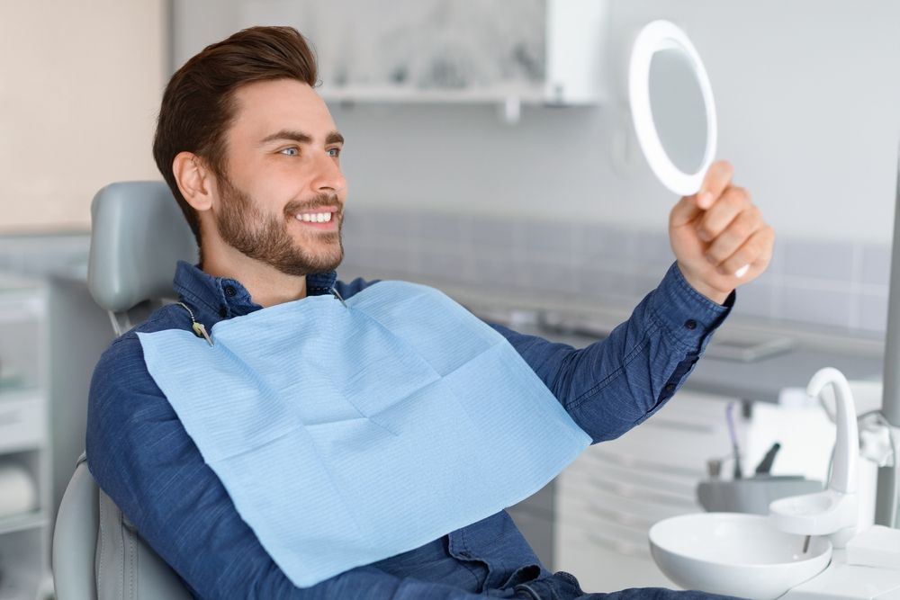 Man viewing his teeth in a mirror after dental care