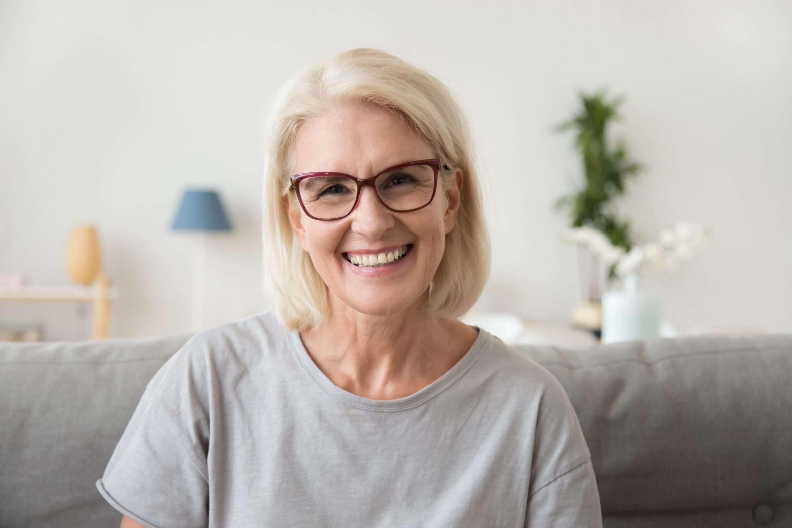 Older woman with glasses smiling after dental care