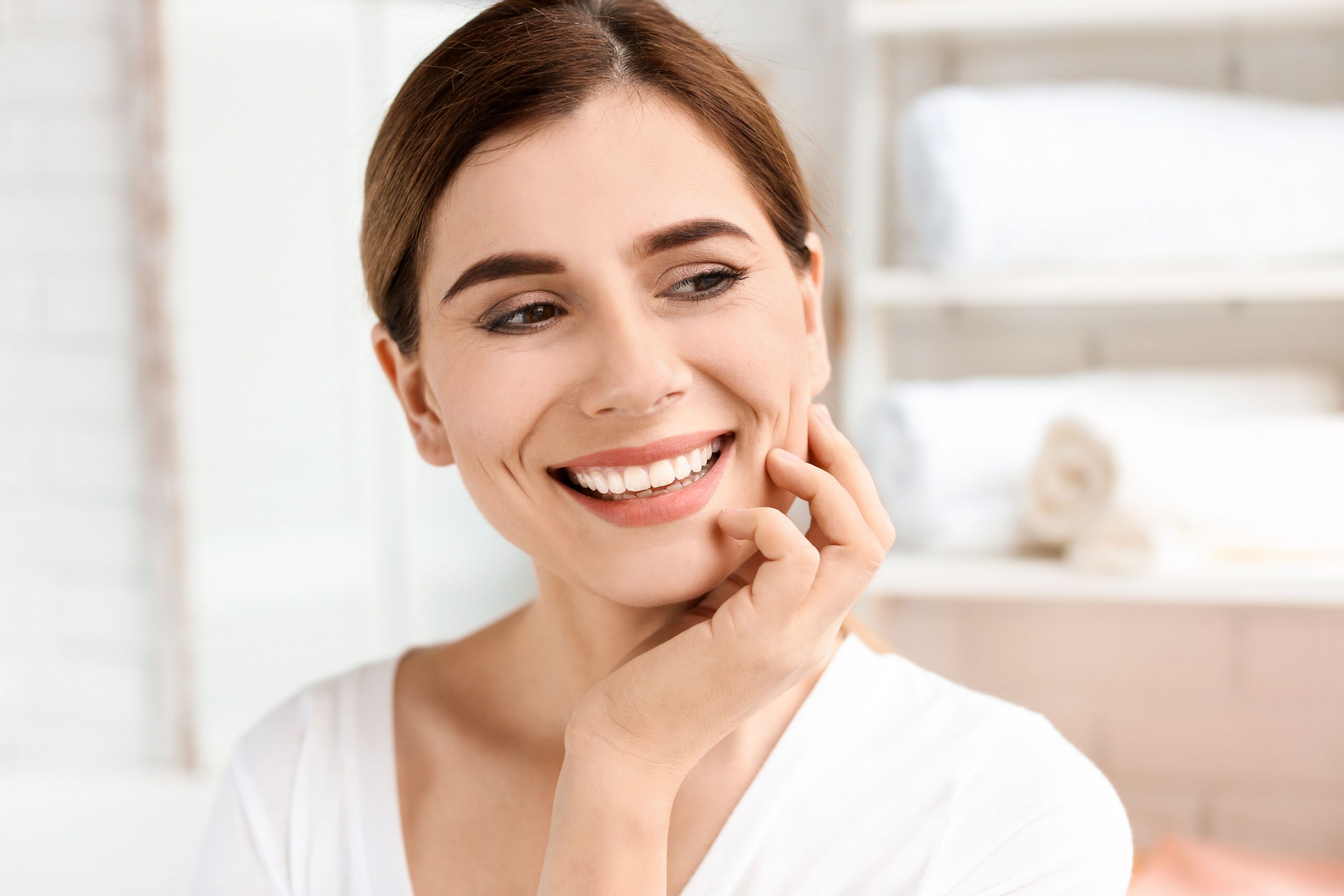 Smiling woman touching her cheek after cosmetic dental care
