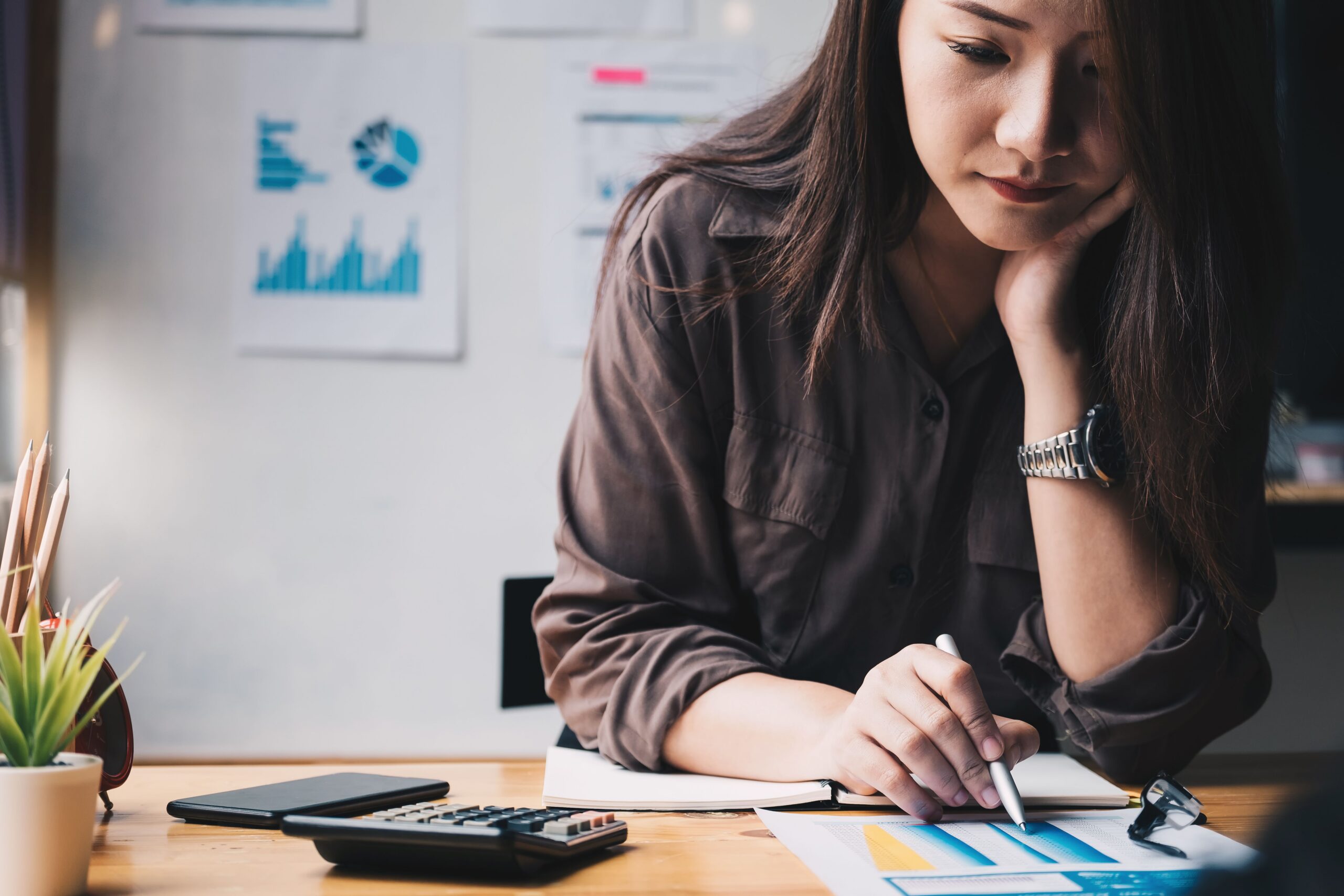 Woman reviewing finances with a calculator and notebook